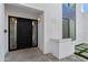 Modern front entrance showcasing a black door with geometric panels, set in a white stucco exterior with artificial turf accents at 4825 N 72Nd Way, Scottsdale, AZ 85251