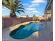 Backyard oasis featuring a refreshing pool, palm tree, and desert landscaping at 573 W Rattlesnake Pl, Casa Grande, AZ 85122