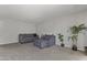 Neutral living room featuring a gray sofa, ottoman, and a large indoor plant creating a calming atmosphere at 6627 W Keim Dr, Glendale, AZ 85301