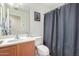 Functional bathroom features a single sink vanity, toilet, and shower with gray curtain at 8429 W Vernon Ave, Phoenix, AZ 85037