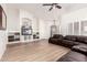 Spacious living room featuring built-in shelves, TV, fan, and hardwood flooring at 12622 W Catalina Dr, Avondale, AZ 85392