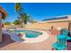 Lush backyard oasis featuring a sparkling pool surrounded by palm trees and a charming rock feature at 12622 W Catalina Dr, Avondale, AZ 85392