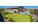Backyard boasts a pristine pool, putting green, desert landscaping, and a covered patio for relaxation and entertainment at 13455 N 142Nd Ave, Surprise, AZ 85379