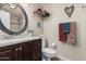 Bathroom featuring a dark wood vanity, round mirror, toilet, and decorative wall hangings at 14212 N Newcastle Dr, Sun City, AZ 85351