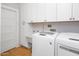 Well-lit laundry room with modern washer and dryer units and ample white cabinet space at 144 W Palm Ln, Phoenix, AZ 85003