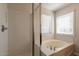Close-up of bathroom featuring a soaking tub and glass shower, enhanced by natural light from nearby windows at 18123 W Lundberg St, Surprise, AZ 85388
