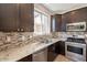 Well-lit kitchen featuring granite countertops, tile backsplash, stainless steel appliances, and dark cabinetry at 18123 W Lundberg St, Surprise, AZ 85388