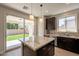 Stylish kitchen showcasing granite countertops, dark cabinets, stainless steel appliances, and access to backyard at 18123 W Lundberg St, Surprise, AZ 85388