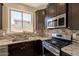 Well-lit kitchen featuring granite countertops, tile backsplash, stainless steel appliances, and dark cabinetry at 18123 W Lundberg St, Surprise, AZ 85388