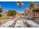 Backyard features a sparkling pool, fire pit, palm trees, and comfortable lounge chairs, creating a resort-like atmosphere at 21256 E Waverly Dr, Queen Creek, AZ 85142
