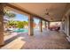 Covered patio with a brick surface, pool, ceiling fans, and lush greenery at 21256 E Waverly Dr, Queen Creek, AZ 85142
