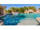 Lush backyard oasis with a large pool, beach entry, and a captivating rock waterfall feature at 21256 E Waverly Dr, Queen Creek, AZ 85142
