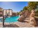 Sparkling pool with a rock waterfall, water slide, and a basketball hoop offers outdoor fun at 21256 E Waverly Dr, Queen Creek, AZ 85142