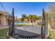 Enclosed trampoline with basketball hoop and lush backyard with artificial turf, creating a fun outdoor recreational space at 21256 E Waverly Dr, Queen Creek, AZ 85142