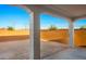 Backyard view from covered patio, showcasing dirt landscaping, brick wall, and clear blue sky at 21287 N 272Nd Ln, Buckeye, AZ 85396