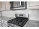 Close up of a stove and microwave inside of a kitchen, accented with granite countertops and stainless steel appliances at 21287 N 272Nd Ln, Buckeye, AZ 85396