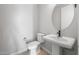 Elegant half-bathroom featuring a pedestal sink, a round mirror, and modern fixtures, exuding minimalist charm at 21288 N 272Nd Ln, Buckeye, AZ 85396