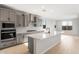 Bright, modern kitchen with gray cabinetry, stainless steel appliances, a quartz island, and wood-look flooring at 21288 N 272Nd Ln, Buckeye, AZ 85396