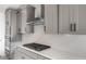 Close-up of a modern kitchen featuring stainless steel range hood and gas cooktop over sleek quartz countertops at 21288 N 272Nd Ln, Buckeye, AZ 85396
