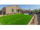 Beautiful backyard featuring artificial grass, a paver patio area with outdoor seating, and manicured landscaping at 2424 S 235Th Dr, Buckeye, AZ 85326