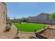 Expansive backyard with a well-maintained artificial lawn, decorative gravel, and a charming patio area at 2424 S 235Th Dr, Buckeye, AZ 85326