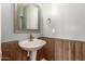 Stylish half-bathroom with a pedestal sink, wood paneling, and a decorative framed mirror at 2765 E Gillcrest Rd, Gilbert, AZ 85298