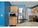 Close up shot of a stainless steel refrigerator, microwave, and wooden cabinets in a blue walled kitchen at 3144 W Maya Way, Phoenix, AZ 85083