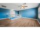 Spacious loft area with blue walls, a ceiling fan, railing, and wood-look floors creates an open and inviting space at 3144 W Maya Way, Phoenix, AZ 85083