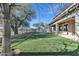 Green backyard with trees lining the fence, a well-kept house, and covered patio with many support beams at 3419 E Rosa Ln, Gilbert, AZ 85297