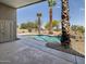 Backyard view of the in-ground pool with palm trees, gravel border and covered patio area at 42476 W Chisholm Dr, Maricopa, AZ 85138