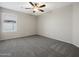 This cozy bedroom features neutral walls, gray carpet and a ceiling fan at 42476 W Chisholm Dr, Maricopa, AZ 85138