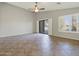 Living room features tile floor, open patio access, a ceiling fan, and white window shutters at 42476 W Chisholm Dr, Maricopa, AZ 85138
