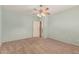 An empty bedroom is shown with carpet flooring, light-colored walls, a ceiling fan and door to the bathroom at 44215 W Granite Dr, Maricopa, AZ 85139