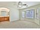 Bedroom with carpet, ceiling fan, a bay window, and a view into the en-suite bathroom at 44917 W Zion Rd, Maricopa, AZ 85139