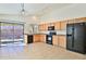 Bright kitchen with wood cabinets, tile flooring, black appliances, and sliding glass door to the backyard at 44917 W Zion Rd, Maricopa, AZ 85139