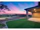 A covered patio overlooks a lush backyard with a modern fence at dusk at 4606 S Ferric --, Mesa, AZ 85212