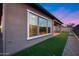 A well-lit backyard featuring a covered patio, lush artificial turf, and a modern stucco exterior at 4606 S Ferric --, Mesa, AZ 85212