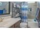Well-lit bathroom featuring a sleek vanity, tile shower with blue-patterned curtain, and ample storage shelves at 560 S 197Th Ave, Buckeye, AZ 85326