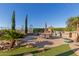 Beautiful desert backyard with lush landscaping, outdoor kitchen, built-in grill, and patio with ample seating at 6022 W Fetlock Trl, Phoenix, AZ 85083