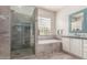 Bright bathroom featuring a double sink vanity, a soaking tub, and a glass-enclosed shower at 6022 W Fetlock Trl, Phoenix, AZ 85083