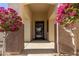 Inviting front entrance with decorative metal door and colorful bougainvillea trees at 6022 W Fetlock Trl, Phoenix, AZ 85083