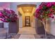 Inviting front entrance framed by colorful flowering trees and a decorative security gate at 6022 W Fetlock Trl, Phoenix, AZ 85083