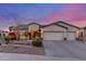 Charming single-story home featuring a 3-car garage and desert landscaping at dusk at 6022 W Fetlock Trl, Phoenix, AZ 85083