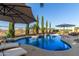 Beautiful backyard pool featuring lounge chairs, umbrellas, desert landscaping, and privacy trees at 6022 W Fetlock Trl, Phoenix, AZ 85083