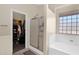 Bright primary bathroom featuring a tub, glass enclosed shower, and walk-in closet at 6904 W Golden Ln, Peoria, AZ 85345