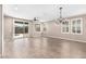 Expansive living room with wood-look tile flooring, plantation shutters, and a sliding glass door for natural light at 8515 W Peppertree Ln, Glendale, AZ 85305