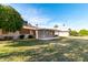 Large grassy backyard featuring mature trees and a charming covered patio area for relaxation at 10420 W Tropicana Cir, Sun City, AZ 85351