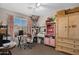 View of a bedroom with carpet floors, a desk, an office chair, a dresser, a ceiling fan, and natural light at 10515 W Pasadena Ave, Glendale, AZ 85307