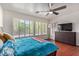 Bright bedroom featuring wood floors, a ceiling fan, and large windows with white shutters at 10558 E Meadowhill Dr, Scottsdale, AZ 85255