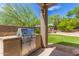 Stainless steel Weber grill in an outdoor kitchen with lush landscaping and seating area at 10558 E Meadowhill Dr, Scottsdale, AZ 85255